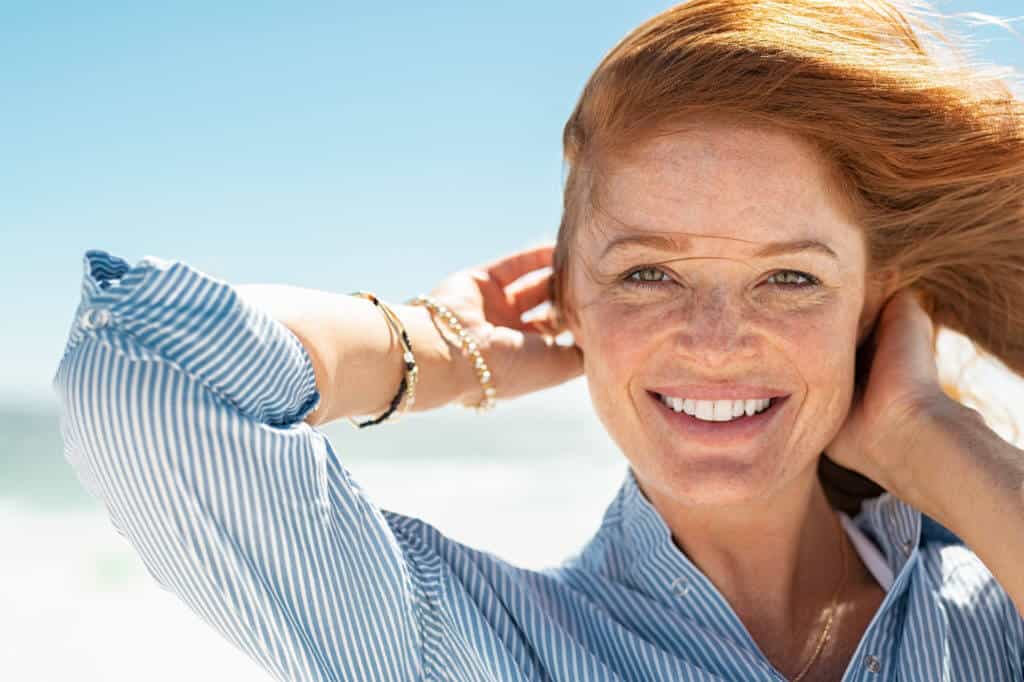 Beautiful Woman with Wind Fluttering Hair Standing at Seaside | Sheperd Integrative Dermatology in Mount Pleasant, SC
