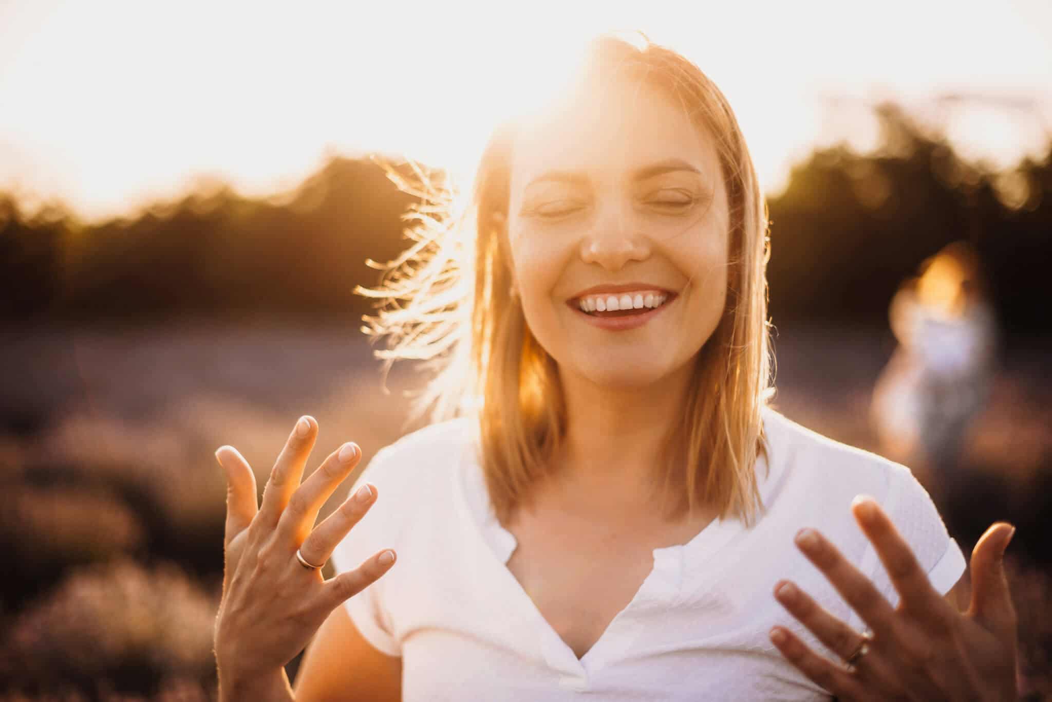 Charming Mother Smiling and Gesturing Against the Sunshine on Field | Sheperd Integrative Dermatology in Mount Pleasant, SC